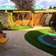 Kindertuin met ronde vormen trampoline, schommel, pergola en houten hoekbank op maat gemaakt