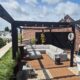 Modern dakterras in Haarlem met zwarte pergola, houten vlonder, eet en loungehoek plus siergrassen