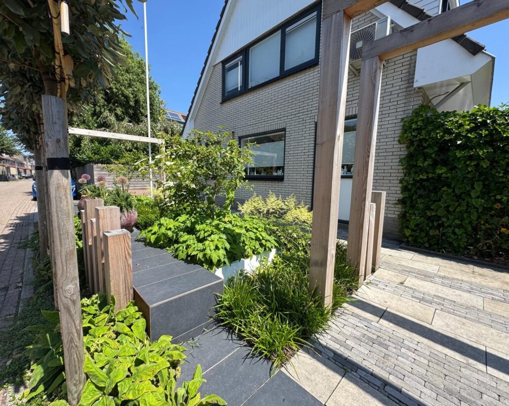 Strakke voortuin met houten pergola, verhoogde border en groene beplanting