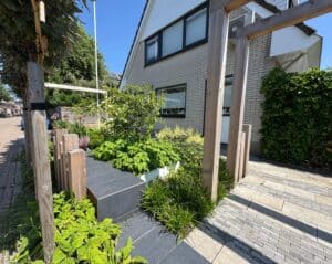 Strakke voortuin met houten pergola, verhoogde border en groene beplanting