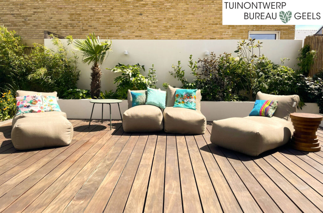 Houten vlonderterras met witte designmuur en lounge stoelen